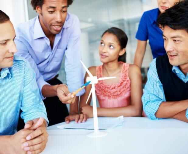 People gathered around a table looking at a model of a windmill